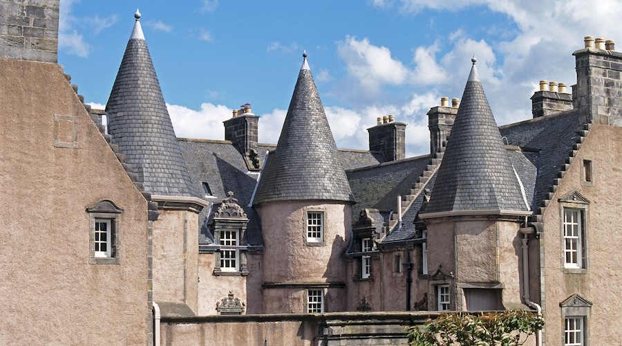 A large, traditional building with a slate roof featuring multiple turrets 