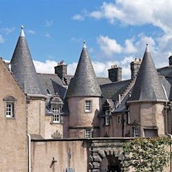 A large, traditional building with a slate roof featuring multiple turrets