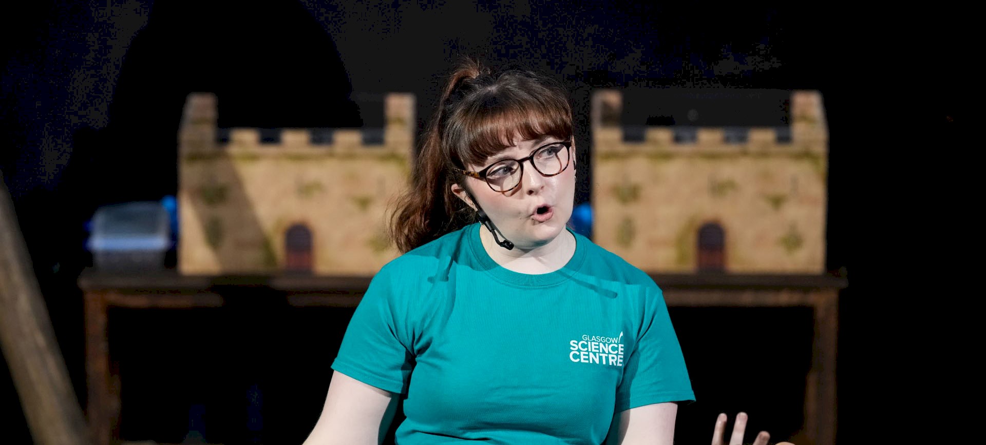 A woman wearing a headset giving a talk. She wears a tshirt with 'Glasgow Science Centre' written on it