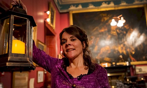 A woman holding a lantern in the Convening Room at Trinity House
