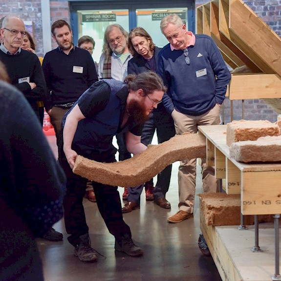 A person demonstrating building energy efficiency to a group, using a display stand