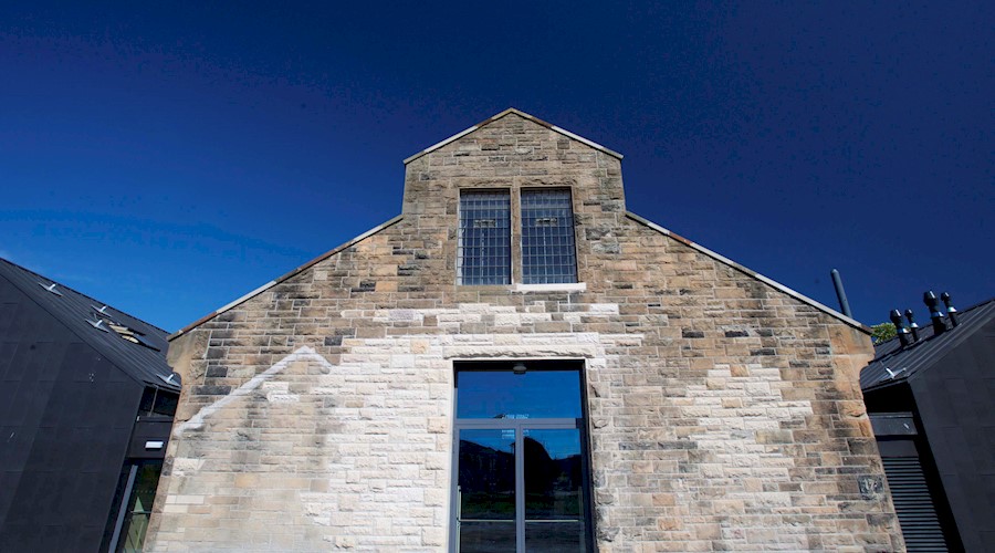 A stone traditional building with two modern black extension wings either side