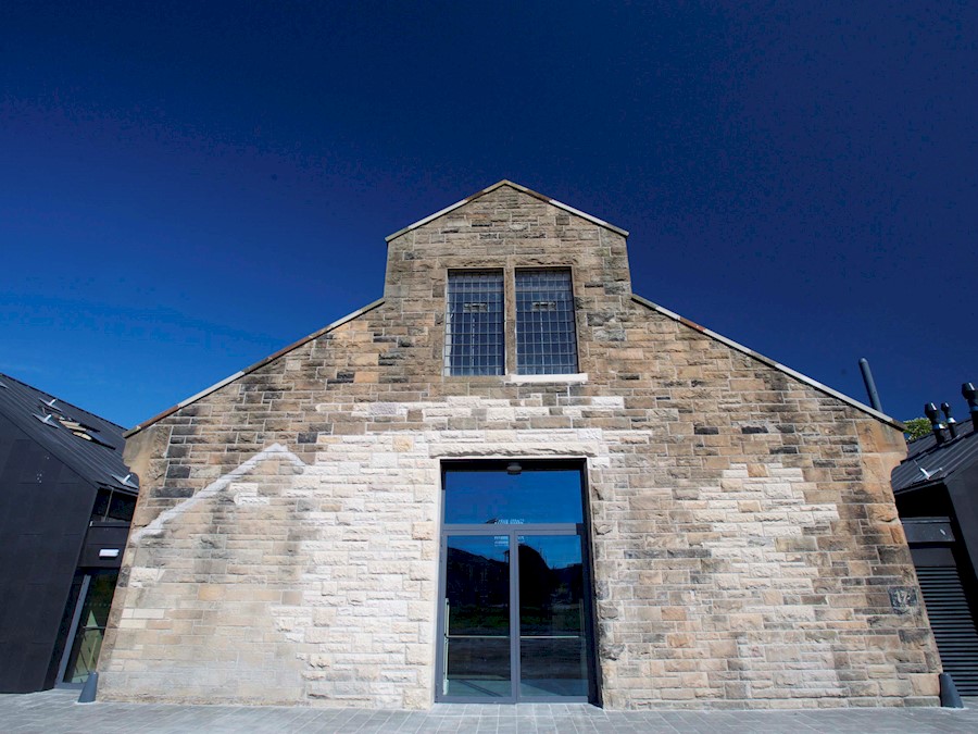 A stone traditional building with two modern black extension wings either side