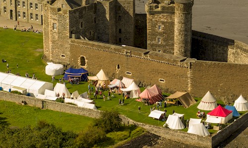 Aerial view of living history camp in the grounds of a castle 