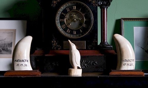 The Masters' Room in Trinity House showing fireplace, clock and scrimshaw carvings of a penguin and whales teeth 