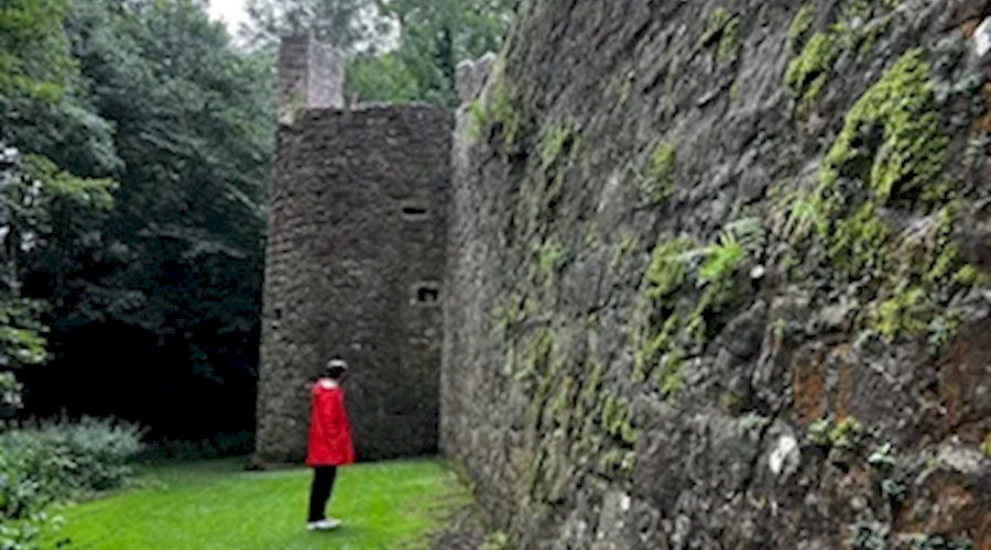 Person in red jacket standing in front of stone wall