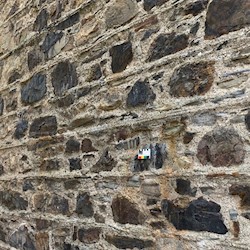 A traditional stone wall of a building. The building is pointed with lime and there's a small card placed on the wall to help identify the lime type.