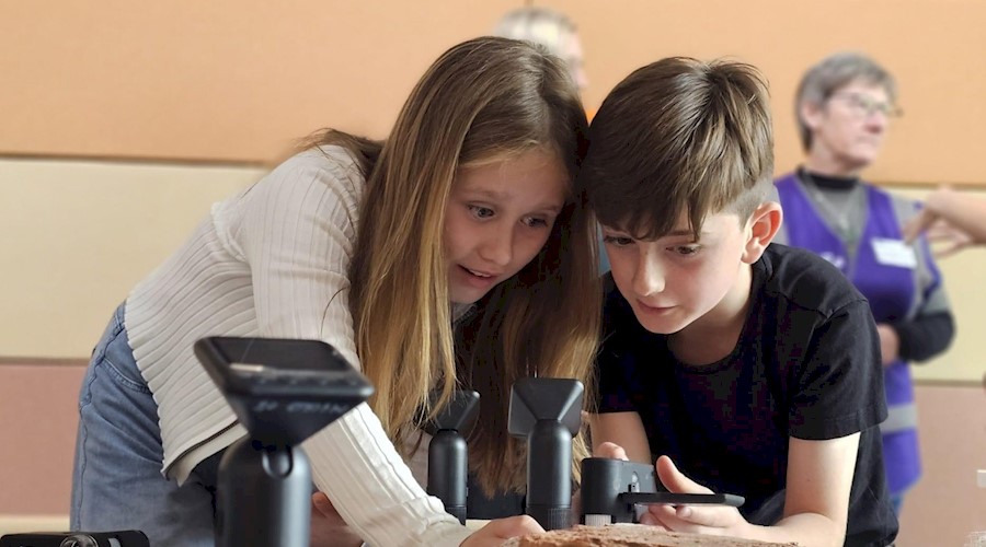 Two children examining building materials like brick and stone using scientific equipment
