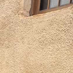 A light orange / yellow lime harled wall on a building with a brown window