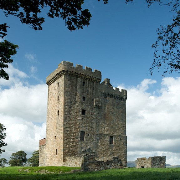 Exterior view of a tower surrounded by lush green grass, blue skies and trees