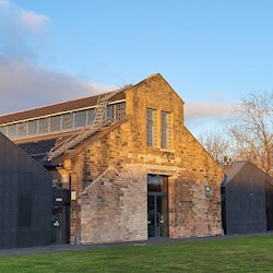 The Engine Shed building - a traditional blonde sandstone building with two modern black wings flanking the original building