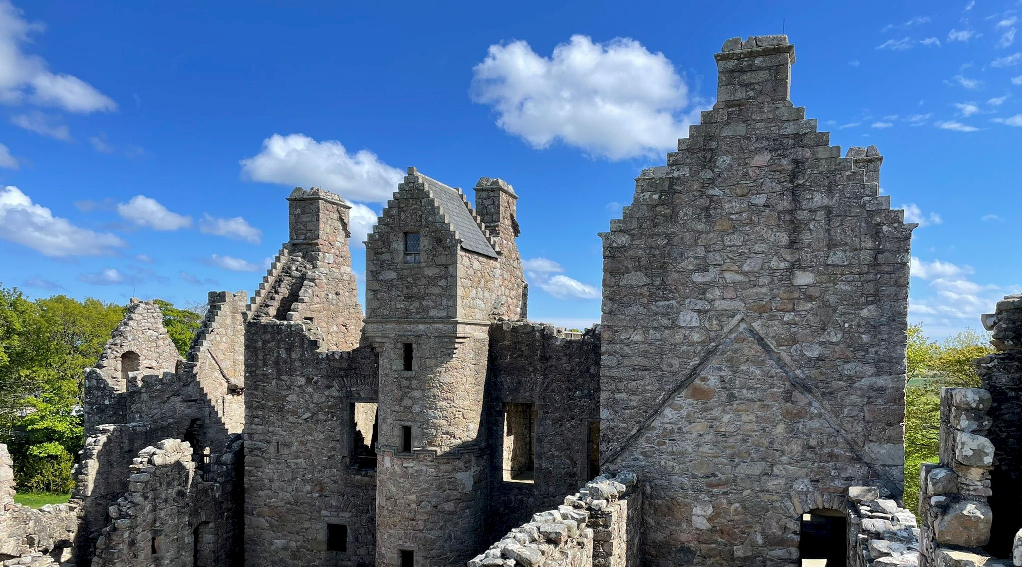View of a castle ruin with clear blue skies and only a dotting of fluffy white clouds