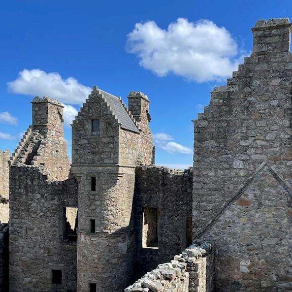 View of a castle ruin with clear blue skies and only a dotting of fluffy white clouds