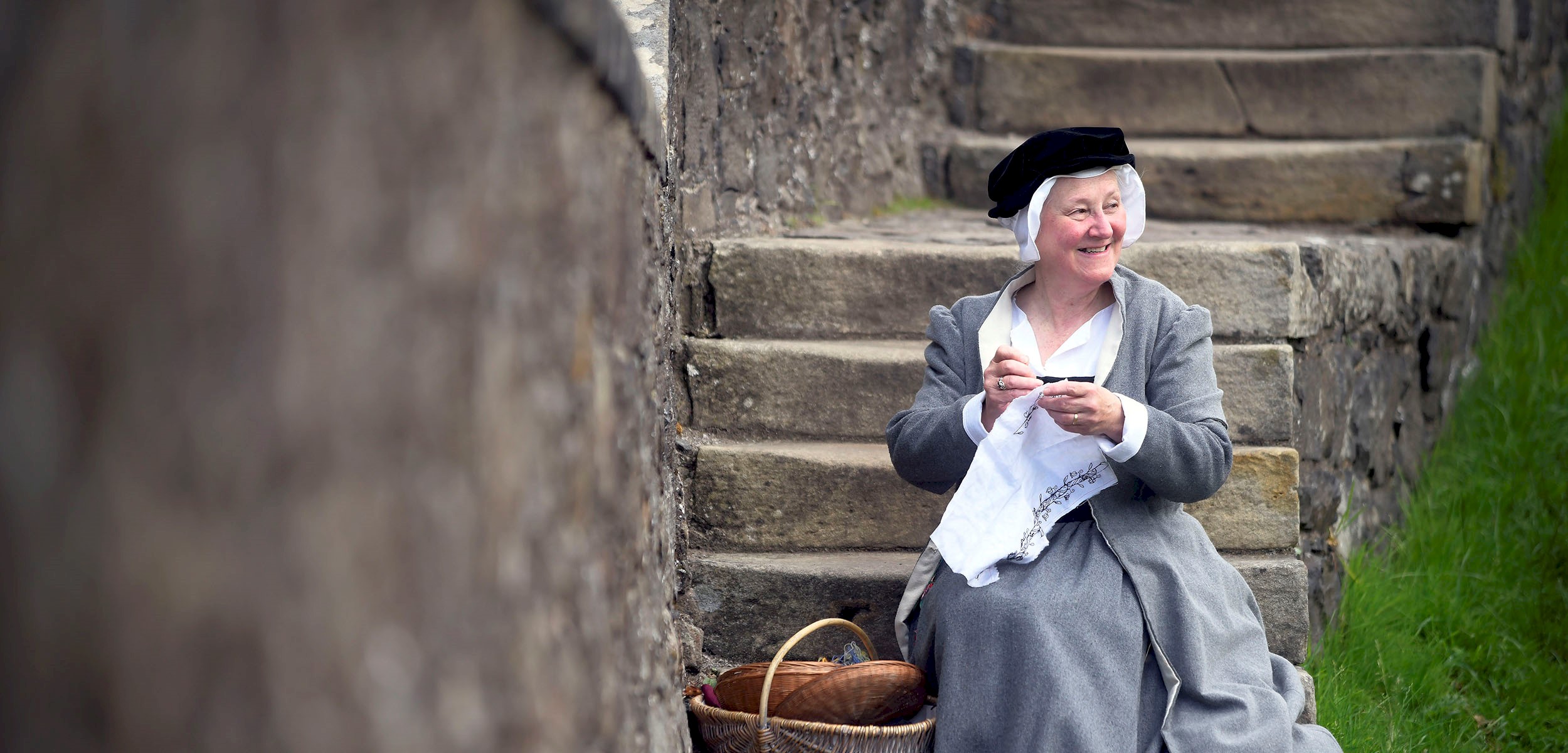 Woman in historical costume sitting on old concrete stairs with wicker baskets