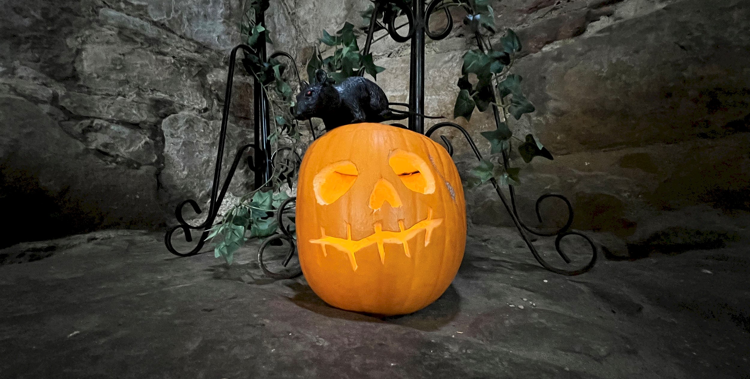 A pumpkin carved and lit for Halloween, on the ground of castle ruins