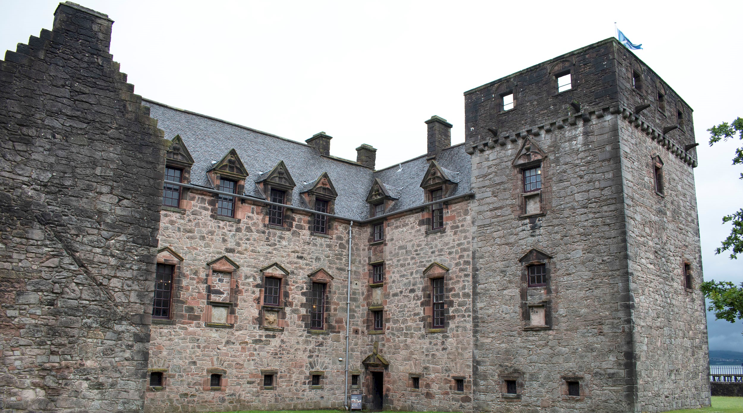 A large stone castle, with a Scottish flag flying from the top right hand corner