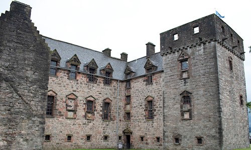 A large stone castle, with a Scottish flag flying from the top right hand corner