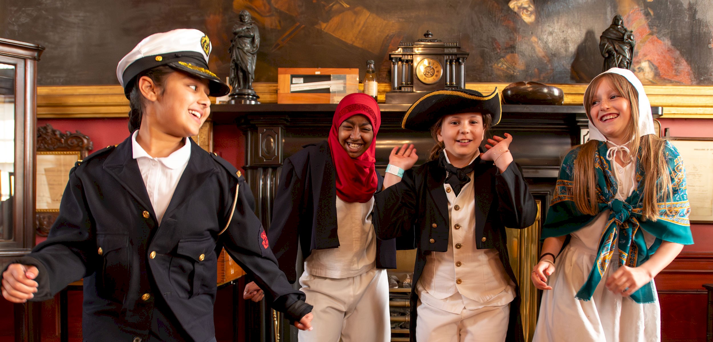Four children dressed up in maritime regalia smiling with their hands in the air