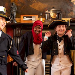 Four children dressed up in maritime regalia smiling with their hands in the air