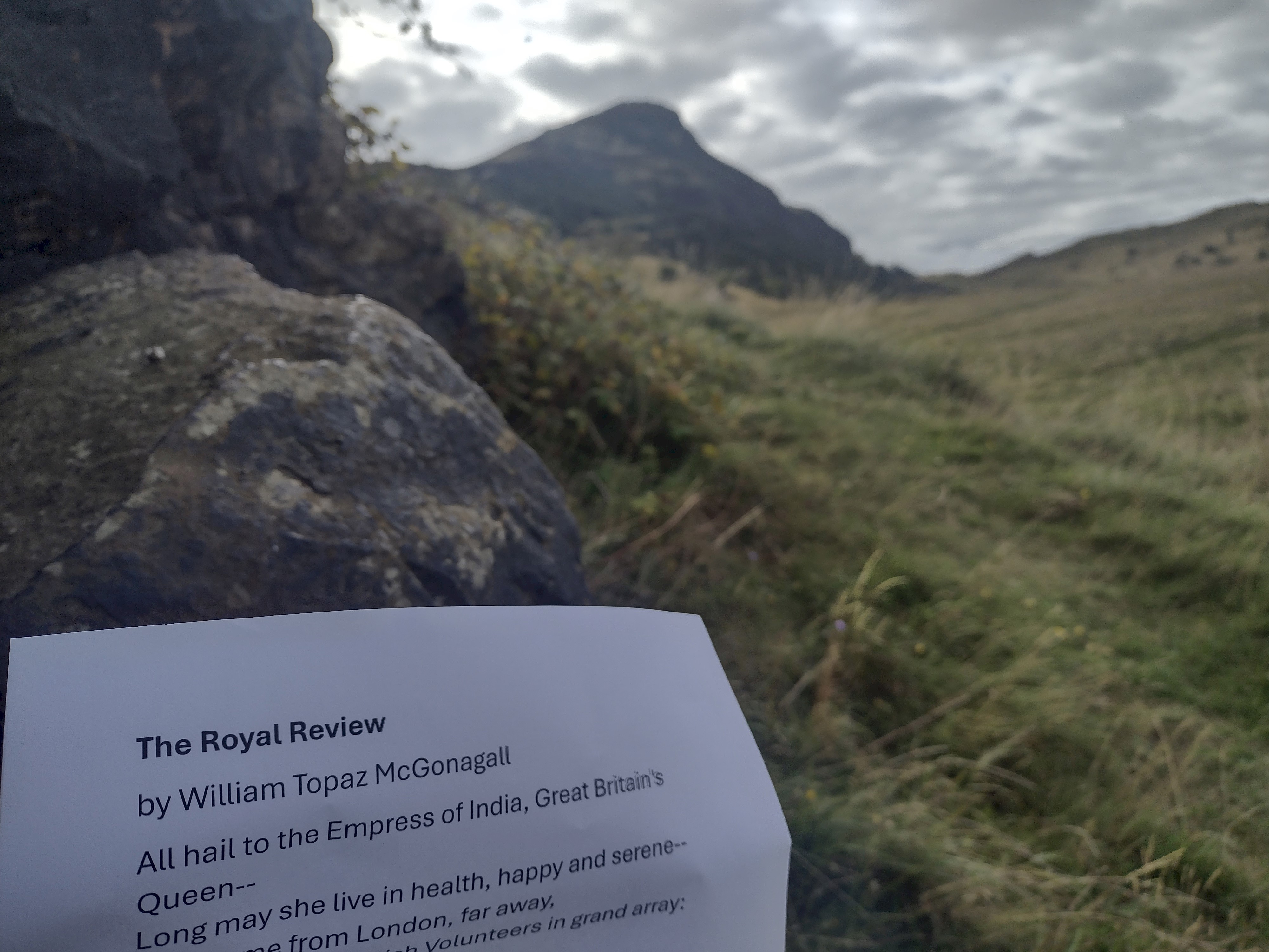 Hills of Holyrood Park and a white sheet of paper with a poem on it