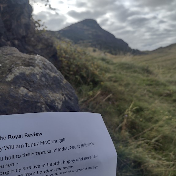 Hills of Holyrood Park and a white sheet of paper with a poem on it