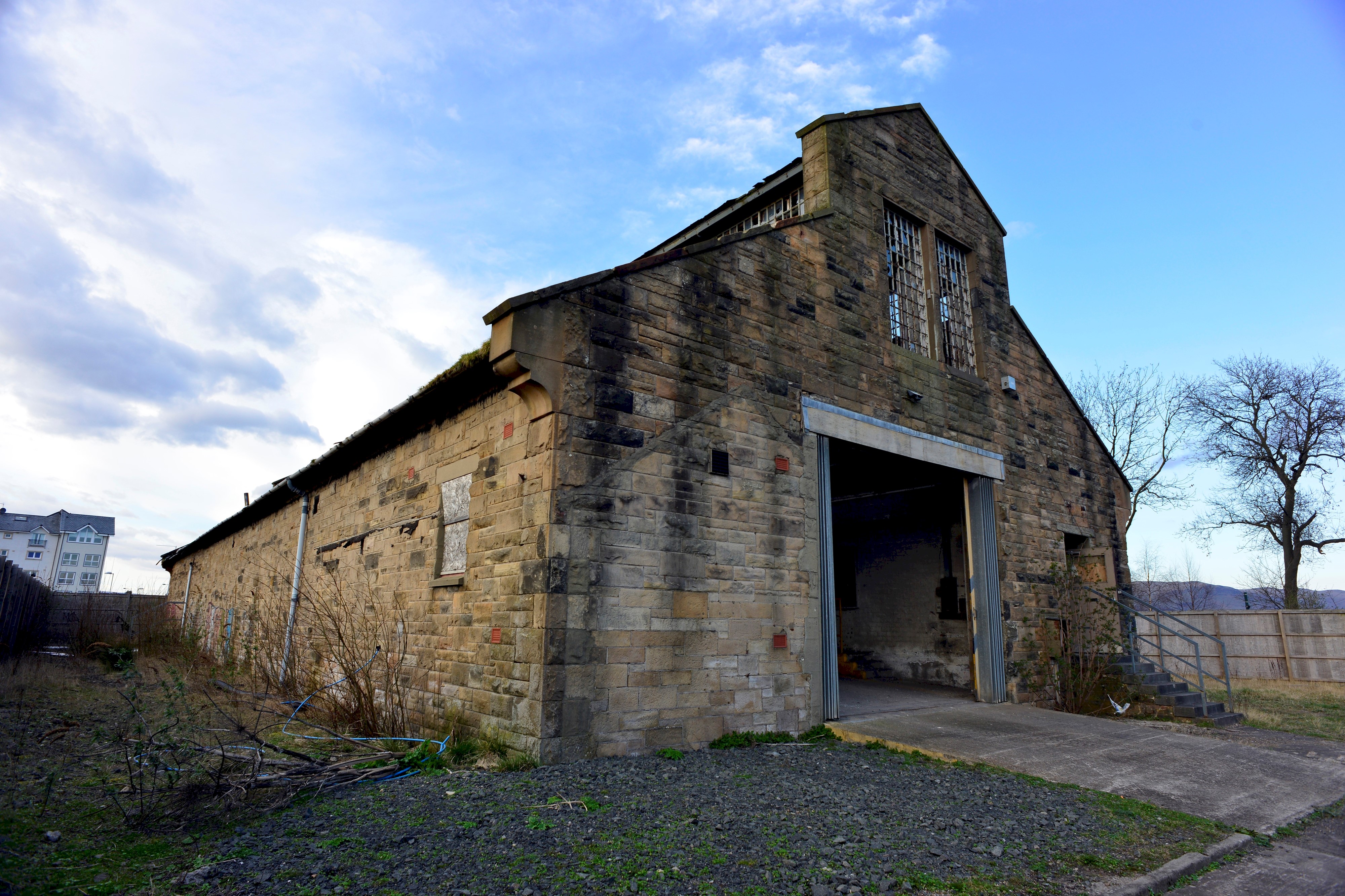 A traditional sandstone Engine Shed building with a large opening on one side