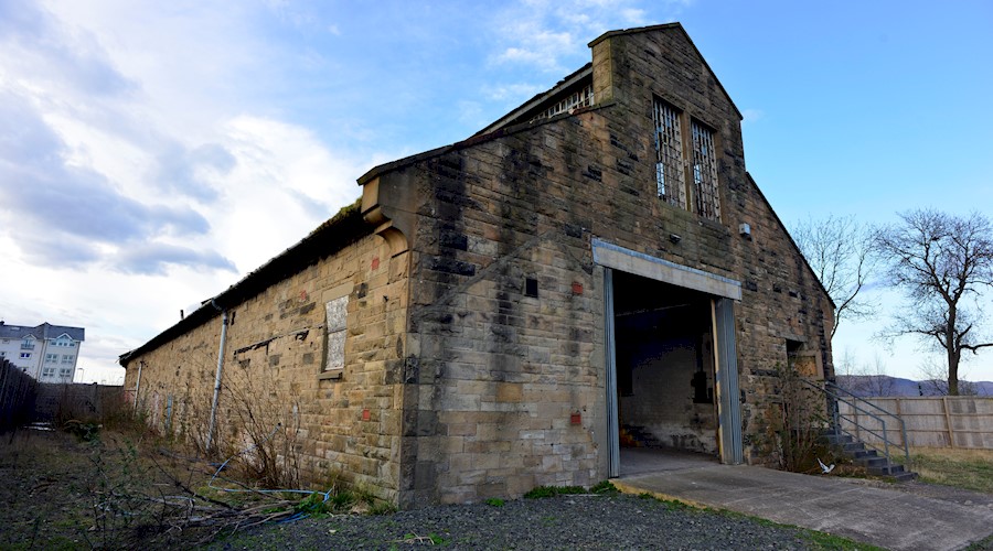 A traditional sandstone Engine Shed building with a large opening on one side