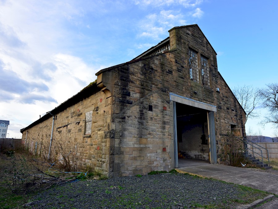 A traditional sandstone Engine Shed building with a large opening on one side