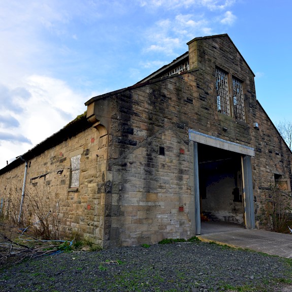 A traditional sandstone Engine Shed building with a large opening on one side