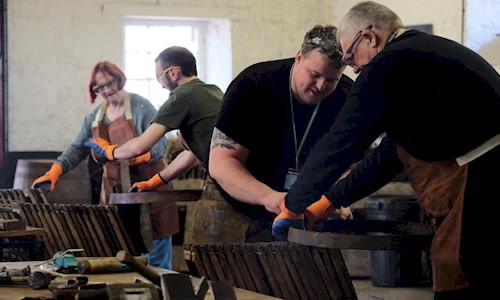 Different people wearing leathery aprons building whisky casks
