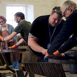 Different people wearing leathery aprons building whisky casks