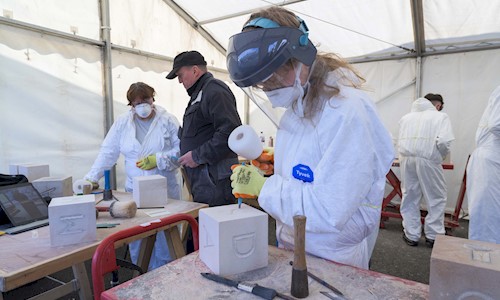 A person carving a letter into a block of stone in a marquee