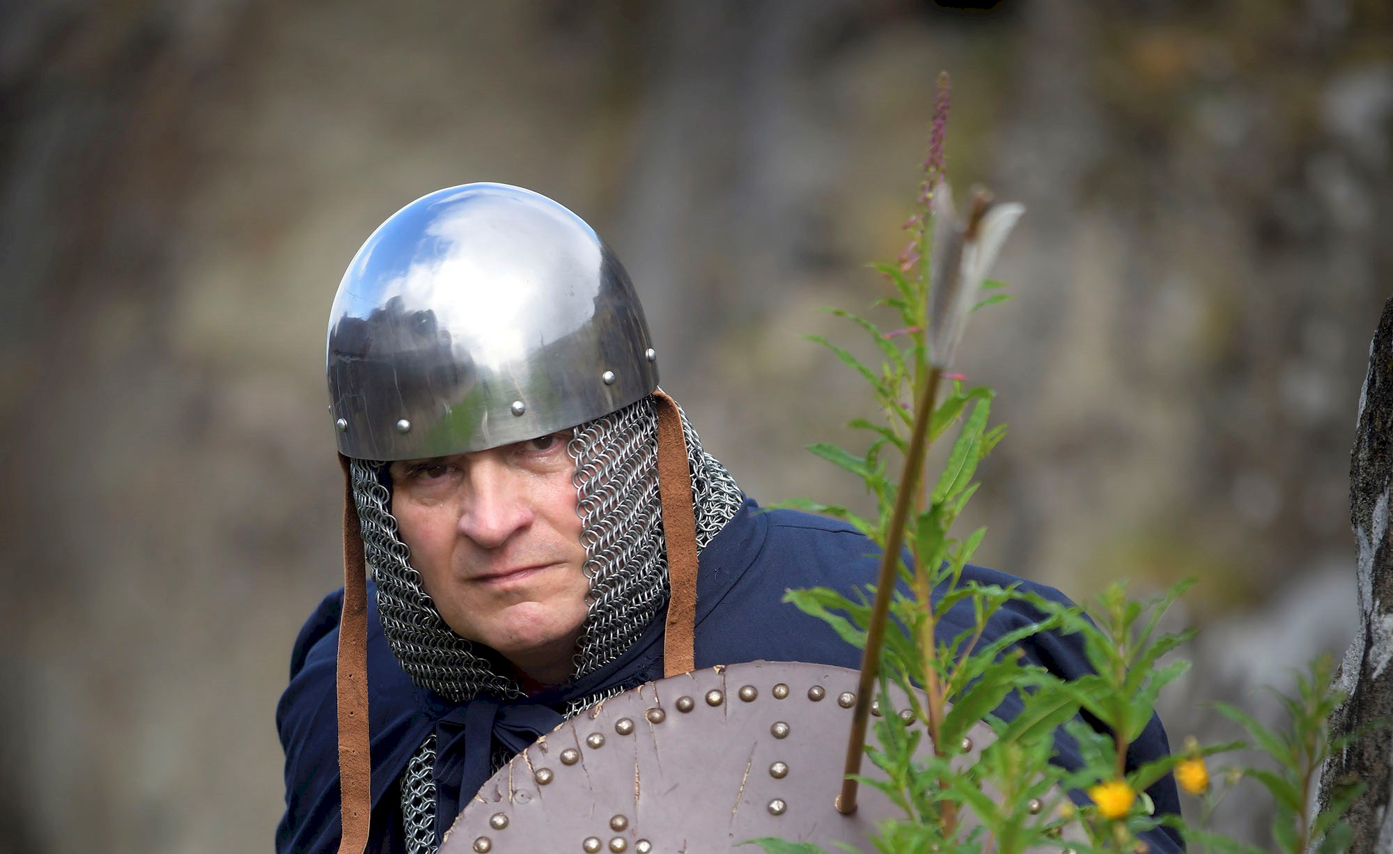 A costumed performer wearing chainmail holding a shield with an arrow fired into it